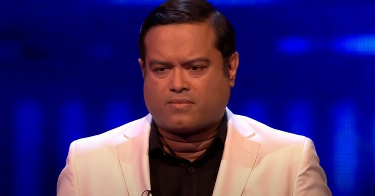 Paul Sinha sat in a white suit while on the ITV show The Chase